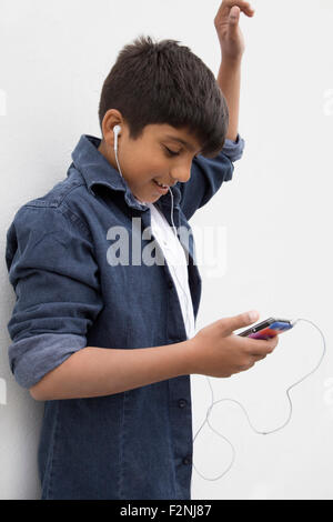 Asian boy à écouter avec des écouteurs de téléphone cellulaire Banque D'Images