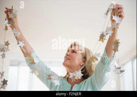 Caucasian woman decorating avec Garland dans la salle de séjour Banque D'Images