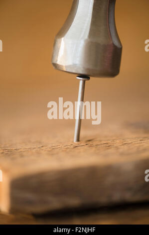 Close up de marteau et clou en planche de bois Banque D'Images