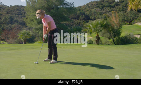 Caucasian woman putting on golf course Banque D'Images