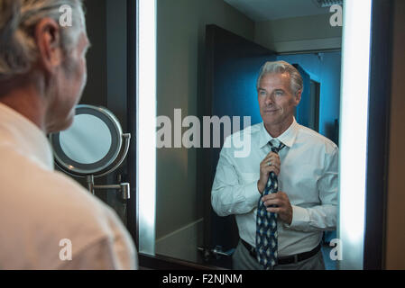 Caucasian businessman adjusting tie in mirror Banque D'Images