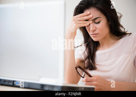 Souligné woman rubbing her front at laptop Banque D'Images