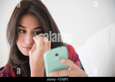 Femme triste à pleurer et using cell phone Banque D'Images