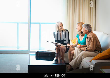 Businesswoman talking to couple on sofa Banque D'Images