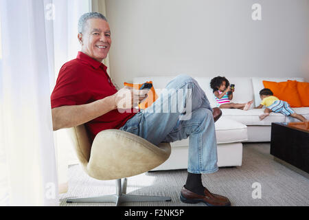 Grand-père et ses petits-enfants relaxing in living room Banque D'Images