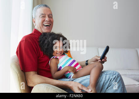 Grand-père et sa petite-fille sitting on sofa Banque D'Images