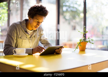 Mixed Race man using digital tablet in cafe Banque D'Images