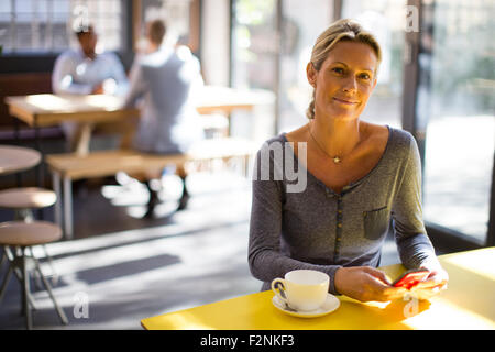 Woman using cell phone in cafe Banque D'Images