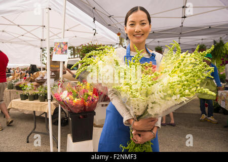 Greffier asiatique holding fresh flowers at farmers market Banque D'Images