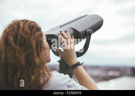 Caucasian woman on urban rooftop admirant cityscape with telescope Banque D'Images