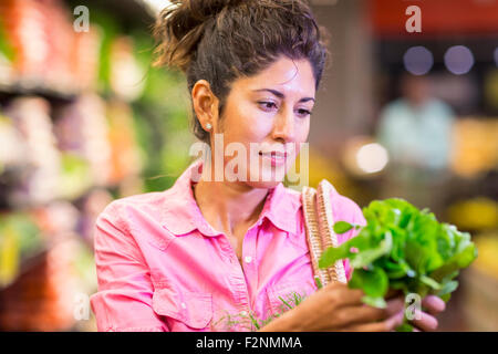 Hispanic woman examinant produire at grocery store Banque D'Images