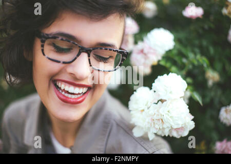 Caucasian woman admiring fleurs sur shrub Banque D'Images