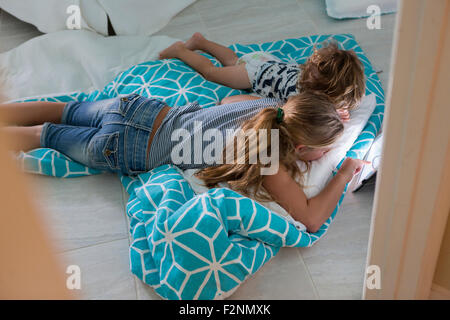 Young brother and sister using digital tablet on bed Banque D'Images