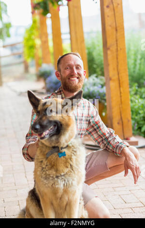 Caucasian man petting dog on patio Banque D'Images