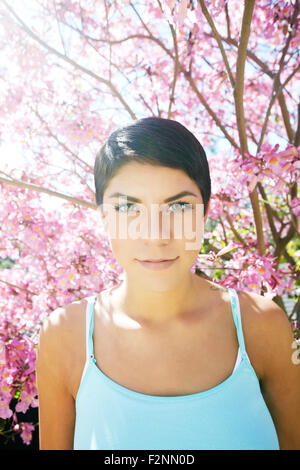 Hispanic woman standing en vertu de l'arbre en fleurs Banque D'Images