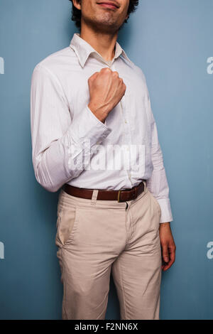 Jeune homme debout par un mur bleu et pompage poing Banque D'Images