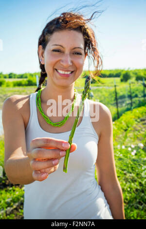 Hispanic woman holding asperges dans jardin Banque D'Images