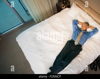 Caucasian businessman fixant on hotel bed Banque D'Images