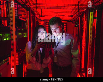 Techniciens using digital tablet in server room Banque D'Images