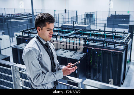 Hispanic businessman using cell phone on balcon sur server room Banque D'Images