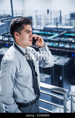 Hispanic businessman talking on cell phone sur balcon sur server room Banque D'Images