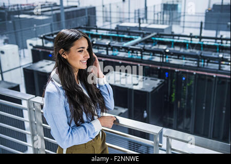 Mixed Race businesswoman using cell phone on balcon sur server room Banque D'Images