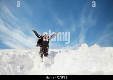 Caucasian girl jumping on snowy hillside Banque D'Images