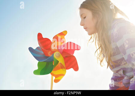 Caucasian girl Playing with pinwheel under blue sky Banque D'Images