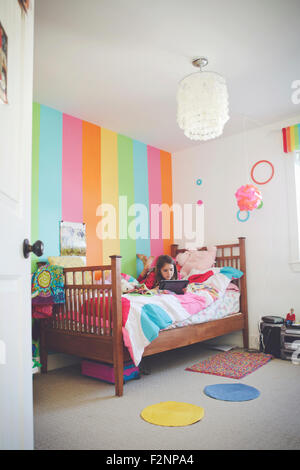 Caucasian girl using digital tablet in bedroom Banque D'Images