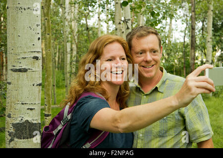 Caucasian couple taking self-portrait in forest Banque D'Images