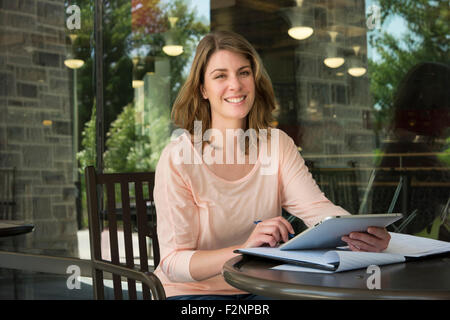 Caucasian student using digital tablet at cafe Banque D'Images