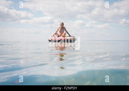 Portrait of teenage girl flottant dans le tube intérieur sur le lac Banque D'Images