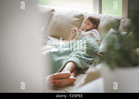 Woman using cell phone on sofa Banque D'Images