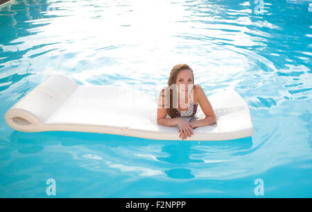 Femme flottant sur radeau dans piscine Banque D'Images