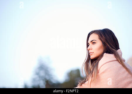 Mixed Race woman wrapped in blanket under blue sky Banque D'Images