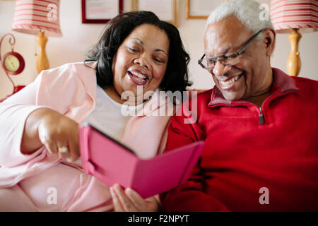 Couple using cell phone in living room Banque D'Images