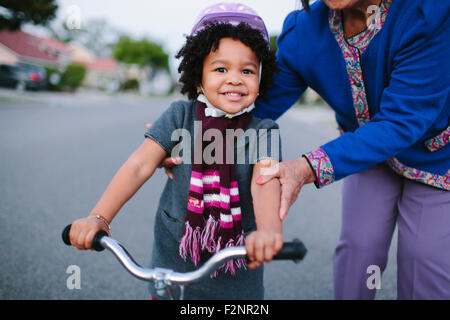 Grand-mère petite-fille d'enseignement à circuler à bicyclette sur la rue de banlieue Banque D'Images
