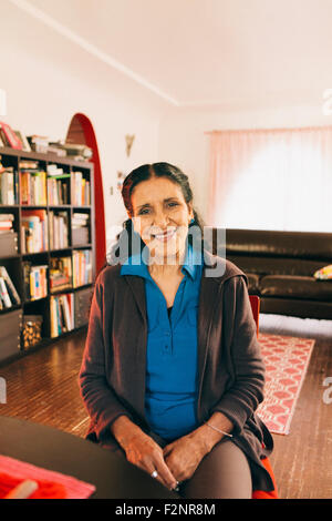 Hispanic woman smiling in living room Banque D'Images