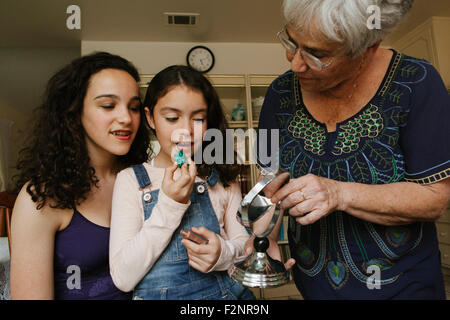 Grand-mère-filles aidant à appliquer le rouge à lèvres dans le miroir Banque D'Images