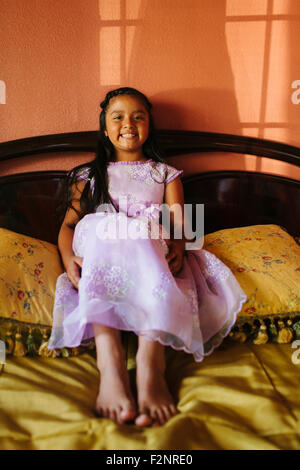 Hispanic girl wearing party dress on bed Banque D'Images