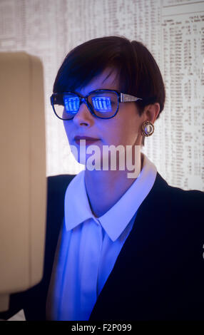 Portrait femme avec écran de l'ordinateur reflètent dans ses lunettes, éclairé par la lumière de l'ordinateur Banque D'Images