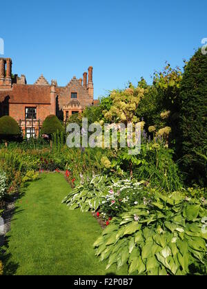 Chenies Manoir et jardin en contrebas avec de belles fleurs vivaces à feuillage vert frais et ensoleillé;avec ciel bleu. Banque D'Images