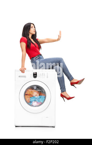 Shot verticale d'une jeune femme attendant le lave-linge pour terminer la blanchisserie et pendant ce temps la regardant les ongles Banque D'Images