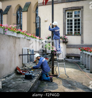 Ingénieurs télécom installant un relais de téléphone cellulaire sur l'ancien bâtiment, France, Europe Banque D'Images