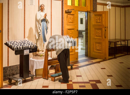 Vieil homme prostating avant vierge Marie statue, dans la basilique de Sainte-Anne de Beaupré, Québec, Canada. Banque D'Images