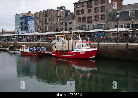 Les bateaux de pêche amarrés dans le port de Sutton, Plymouth, UK avec des boutiques et des cafés sur le quai Banque D'Images