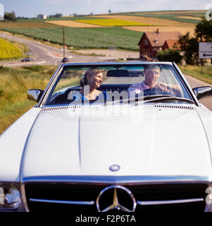 Couple au volant d'une voiture décapotable Mercedes on country road, Alsace, France Europe Banque D'Images