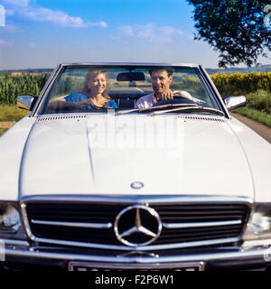 Couple au volant d'une voiture décapotable Mercedes on country road, Alsace, France Banque D'Images