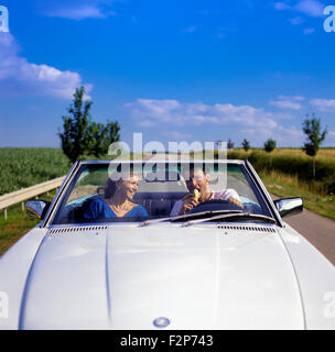 L'homme manger une banane en conduisant une voiture décapotable Mercedes on country road, Alsace, France, Europe Banque D'Images