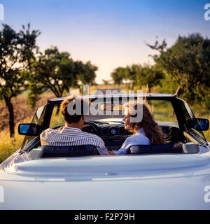 Vue arrière d'un couple au volant d'une Mercedes décapotable voiture sur une route de campagne au coucher du soleil, Alsace, France, Europe, en couple au volant dans le soleil couchant in convertible Banque D'Images